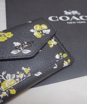 黒と黄色の模様のCOACHの折りたたみ財布の画像